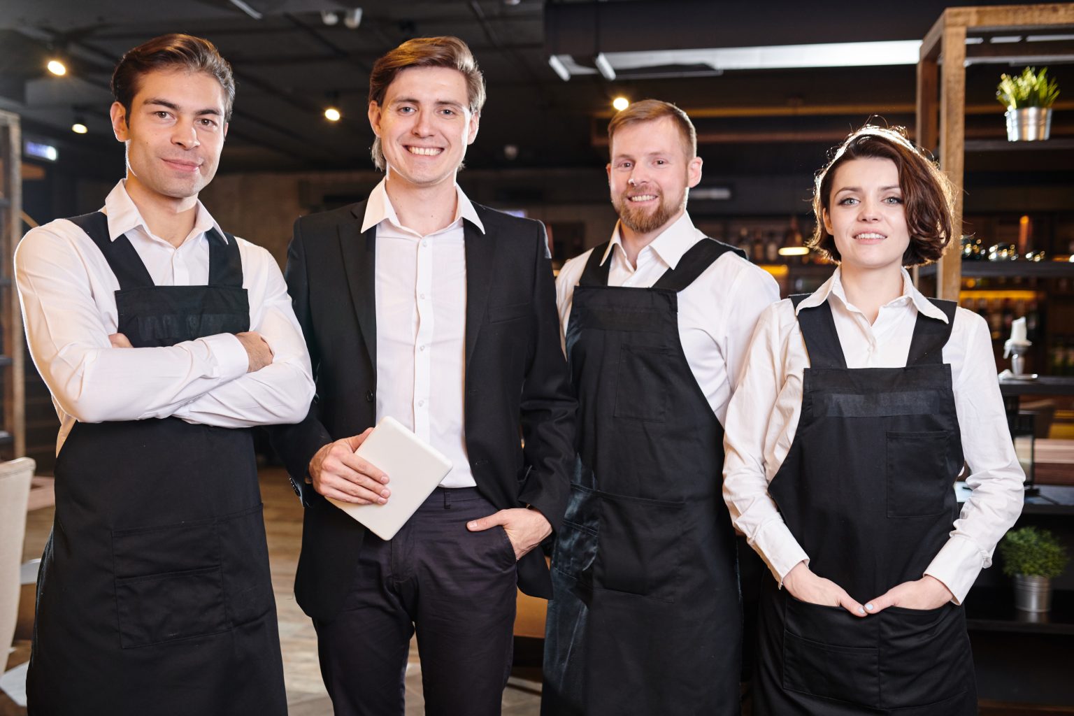 Team of restaurant professionals in ahead of manager standing in line and smiling at camera